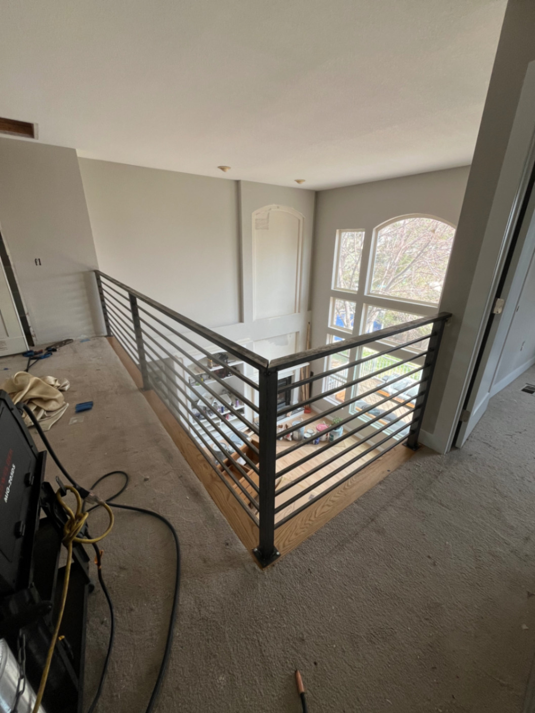 Finished black steel horizontal-bar loft railing with wood cap
