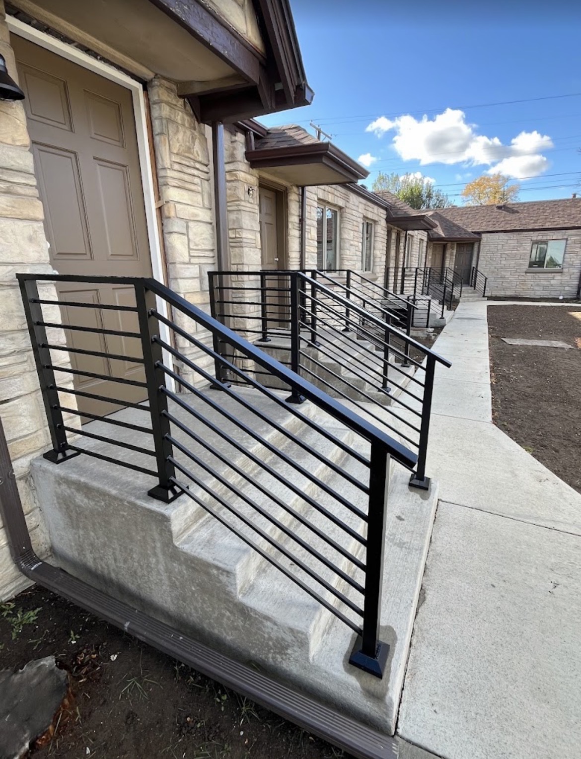 Row of modern horizontal-bar steel railings on stone entries