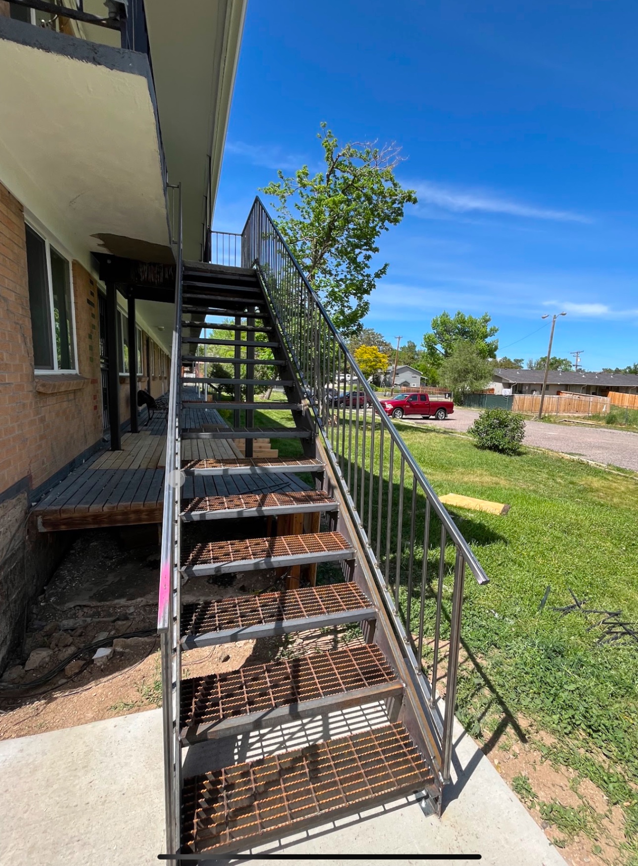 Steel apartment stairway with bar-grating treads and horizontal rails