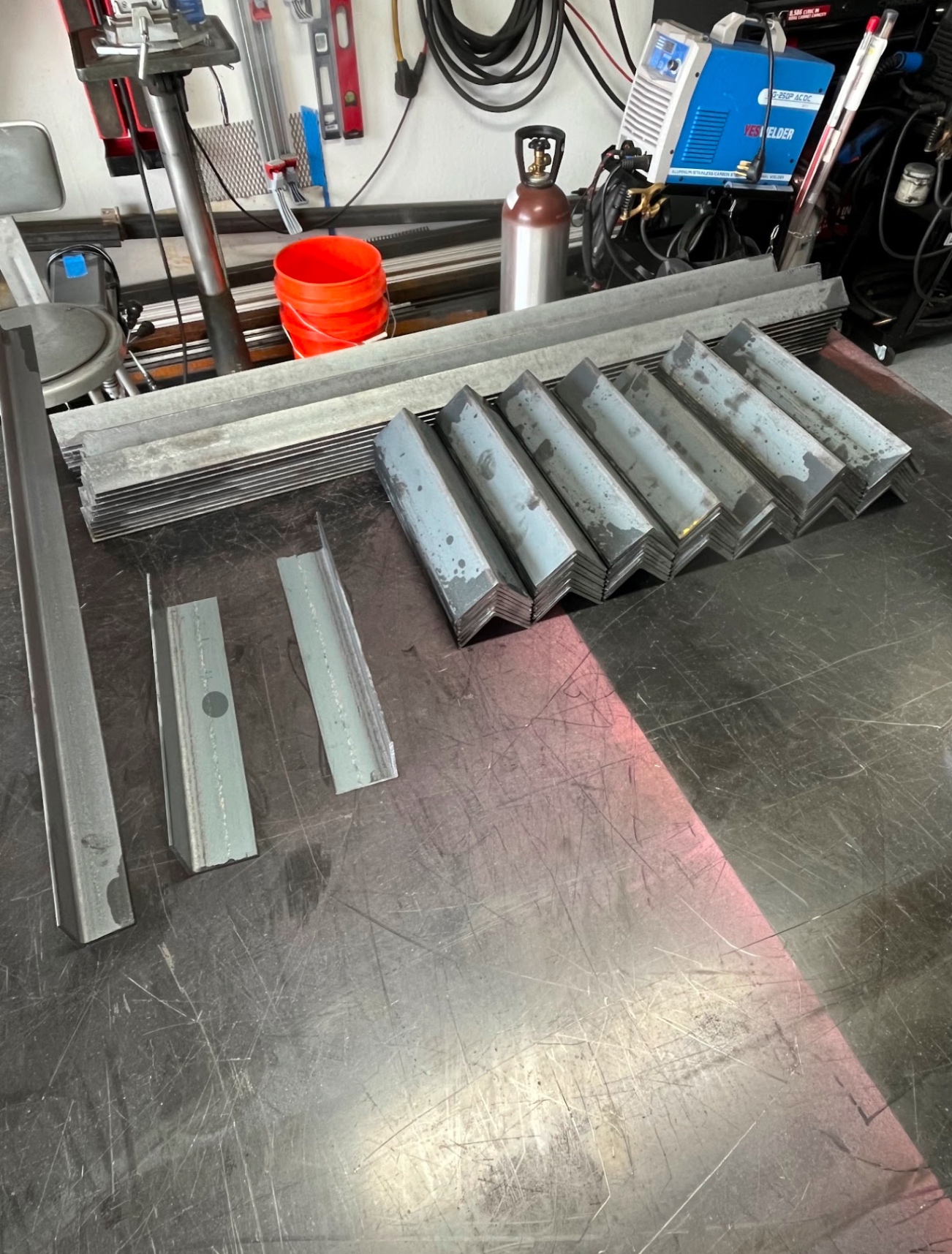 Stacked steel angle iron stock ready for fabrication in shop