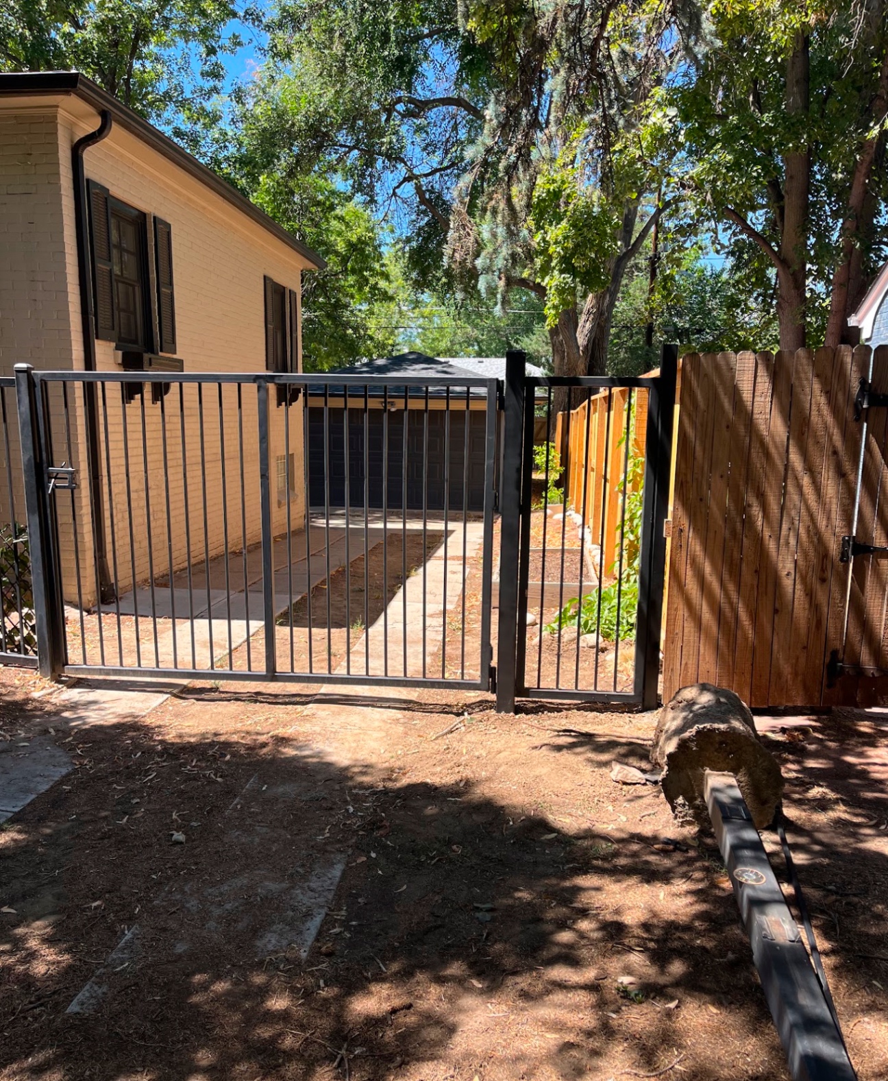Black steel double gate opening to backyard alongside cedar fence