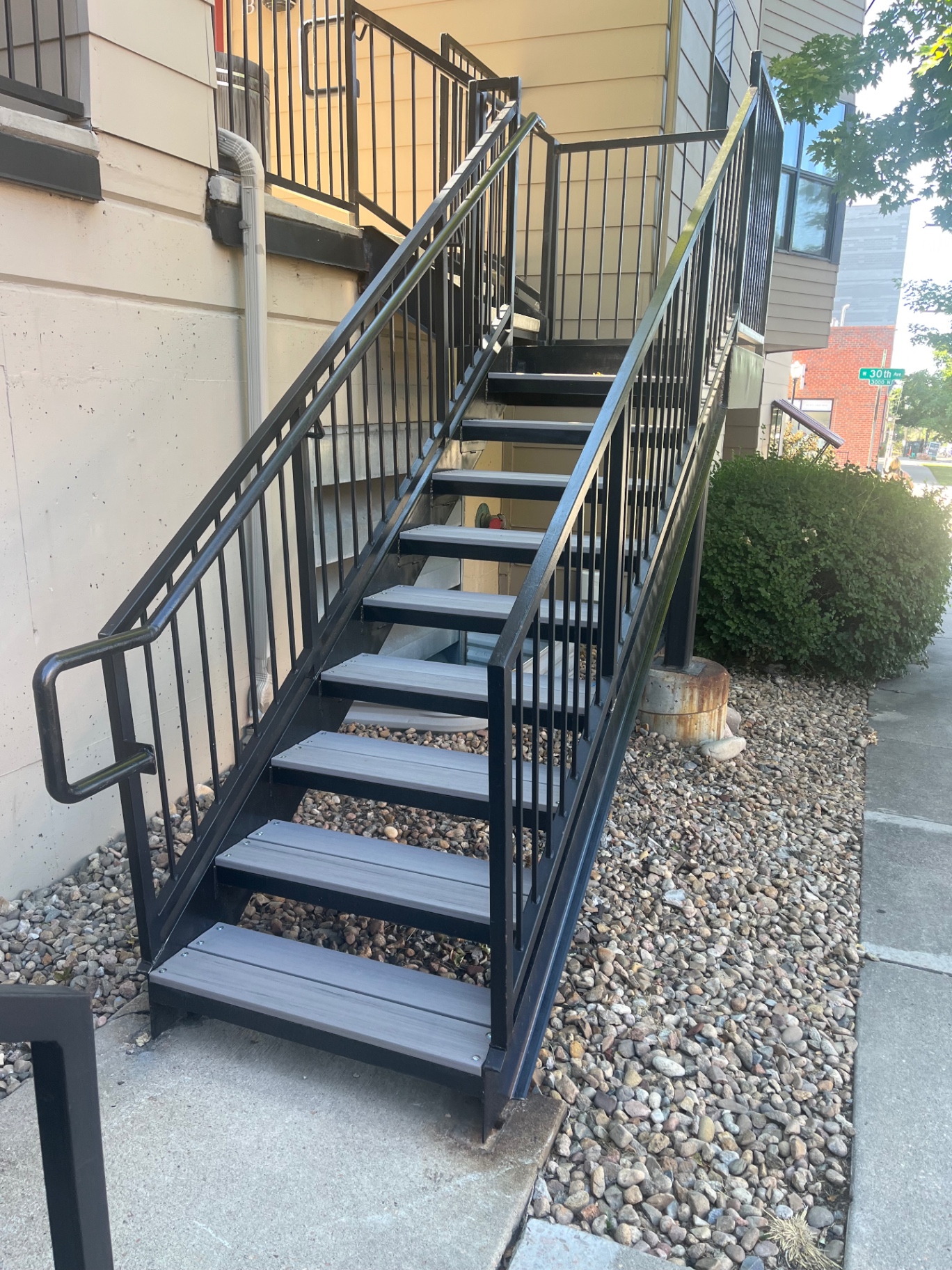 Tall black steel stairway with composite treads beside apartment