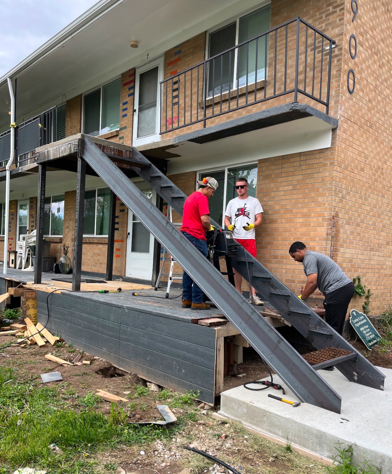 Crew installing custom steel apartment stairway and balcony framing