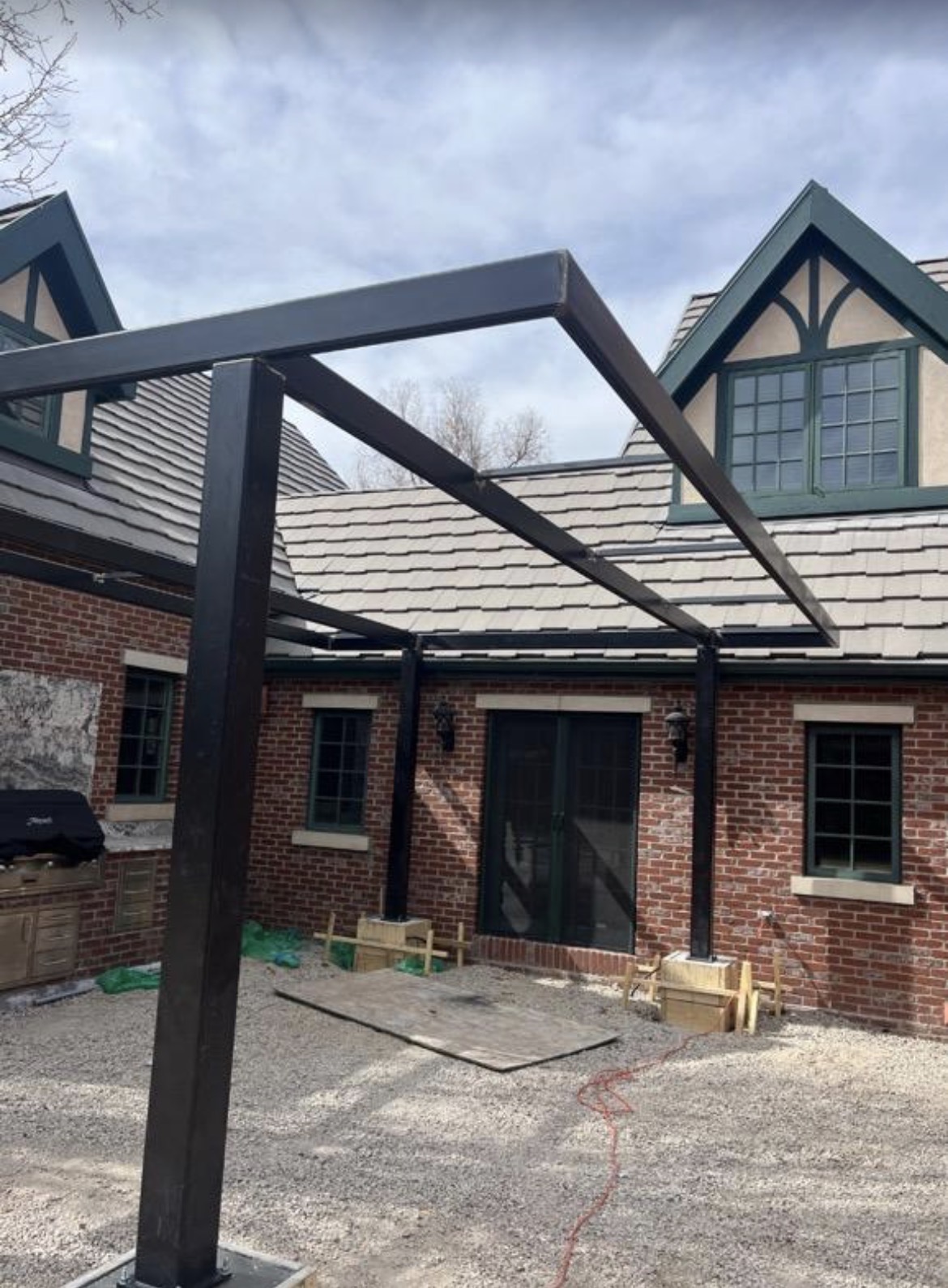 Custom steel pergola frame against brick home