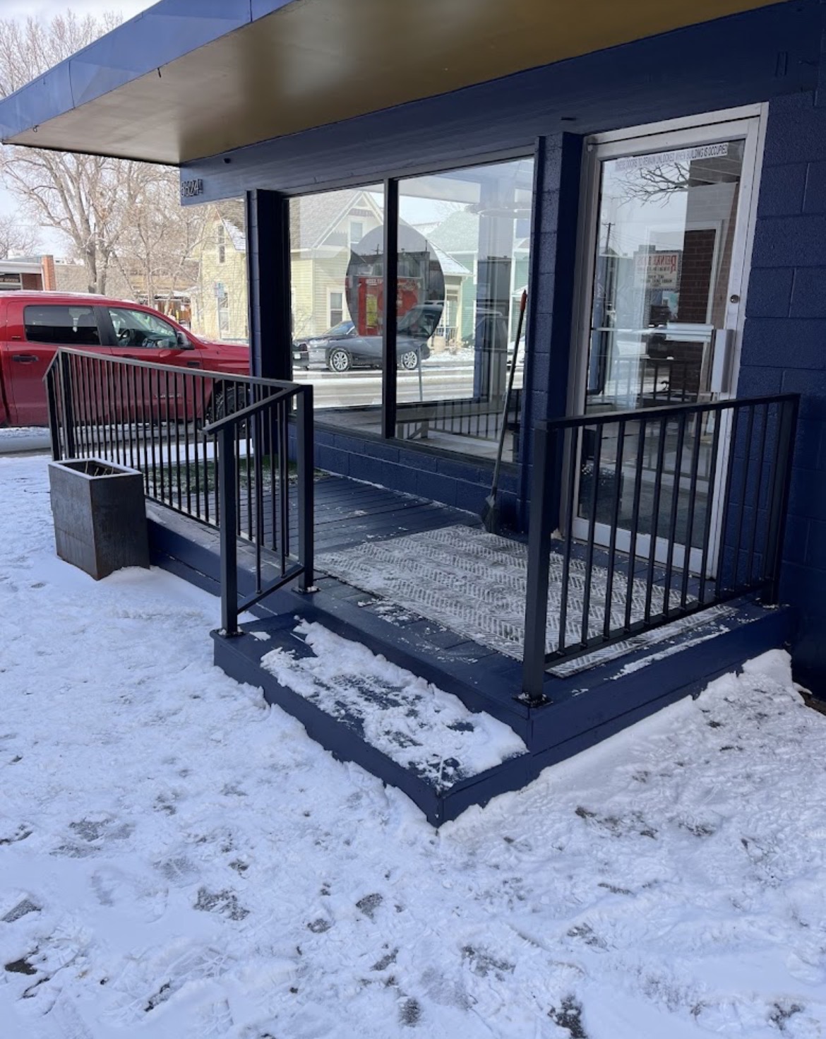 Black steel porch railing at storefront in snow