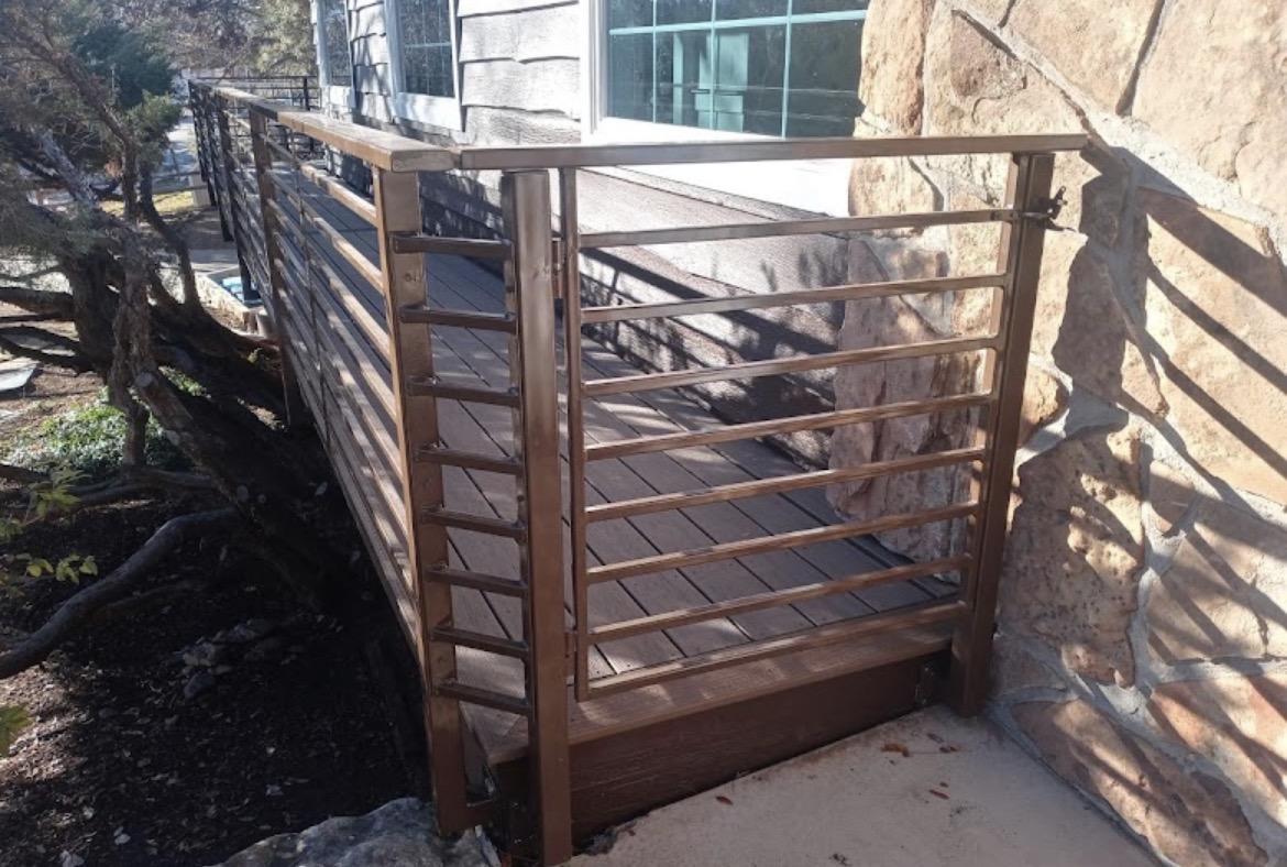 Bronze horizontal steel deck railing beside stone wall