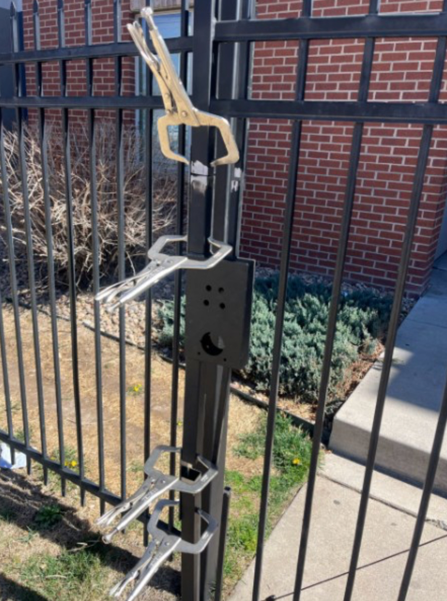 Welding clamps holding steel fence post latch bracket during install