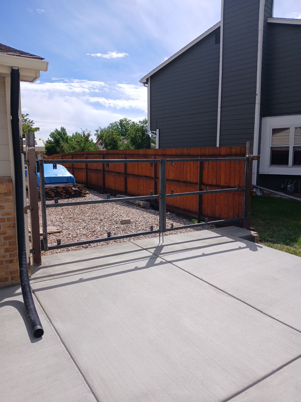 Steel-framed cedar driveway double gate on concrete pad