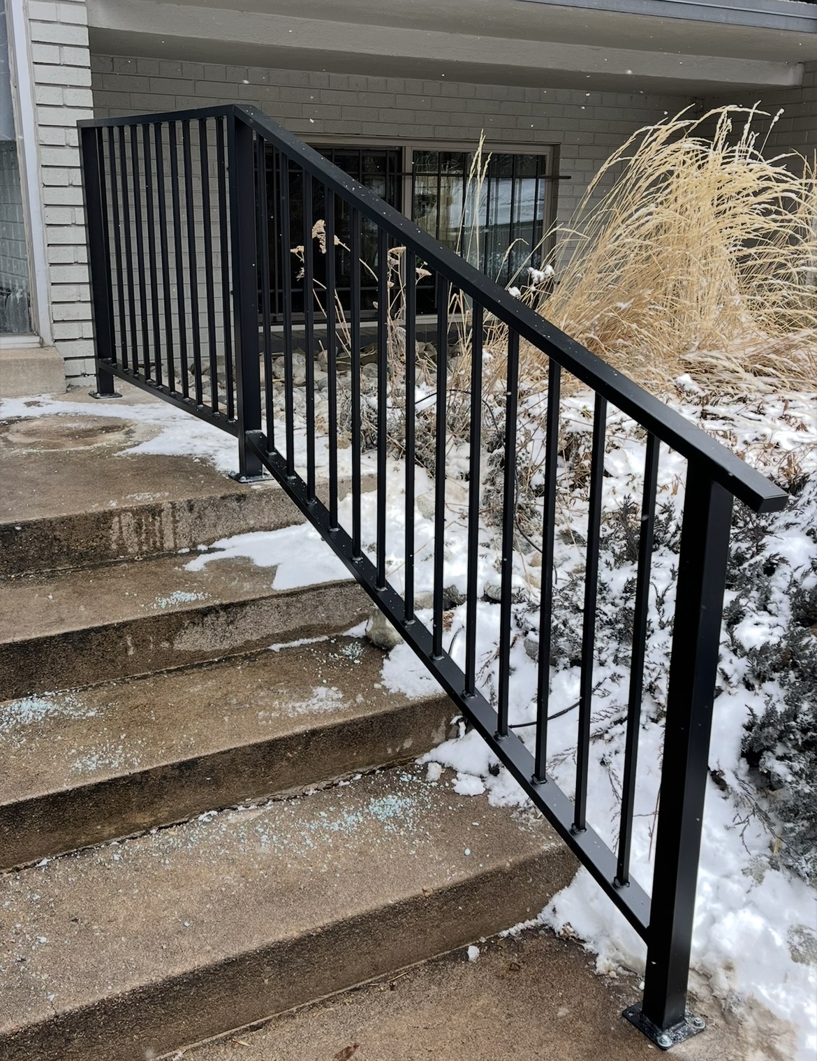 Black steel step railing on snowy front steps