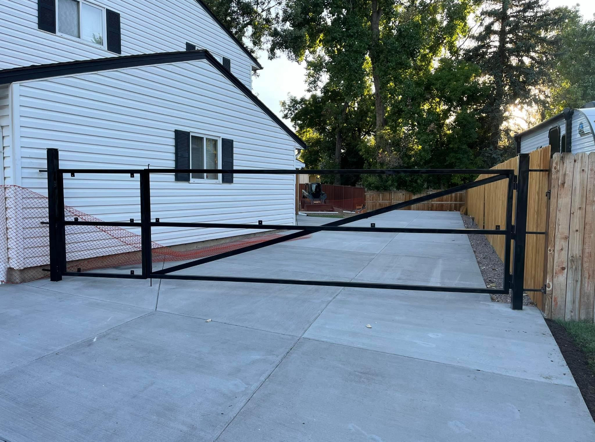 Black steel driveway gate between homes