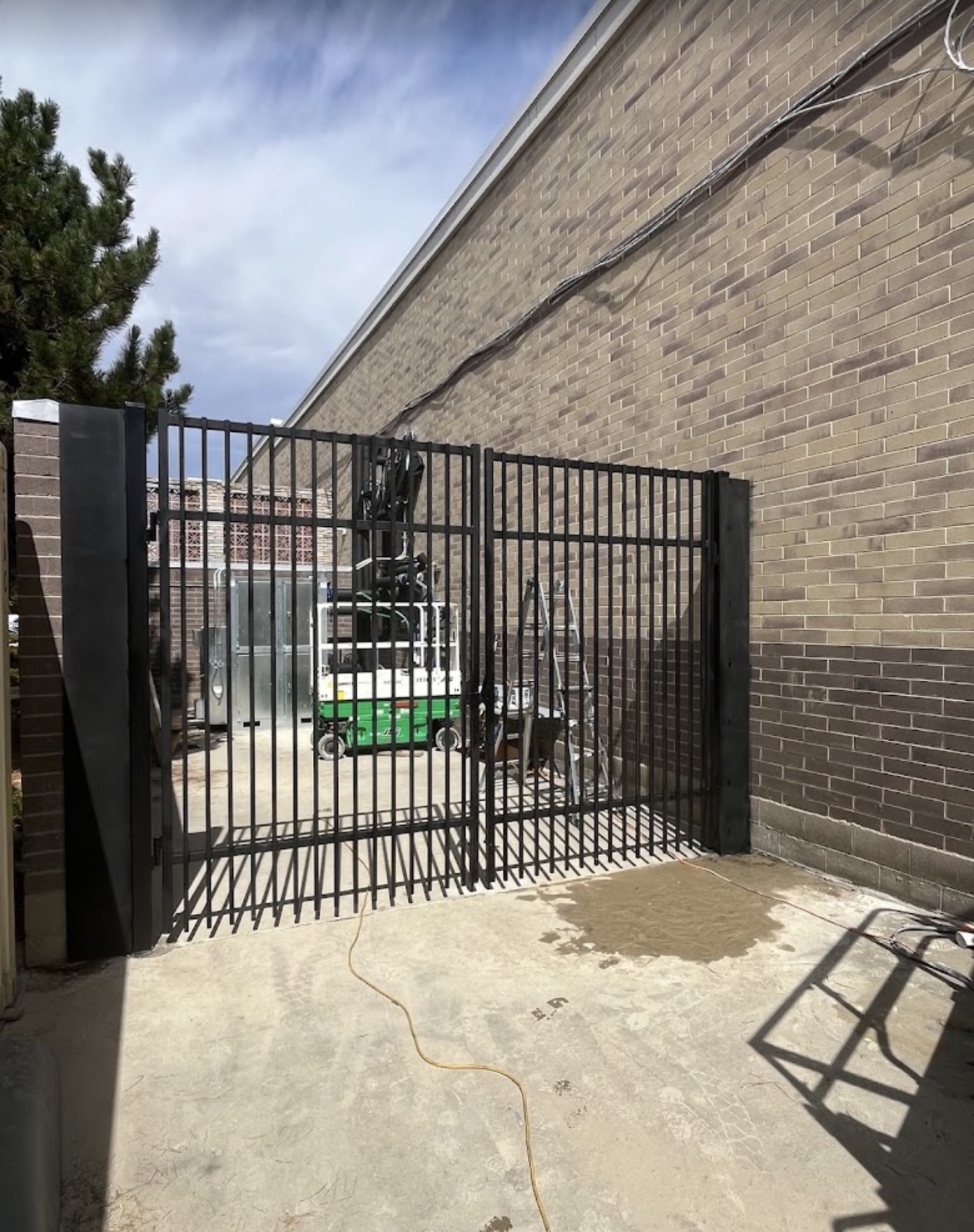 Tall steel side-yard security gate against brick wall